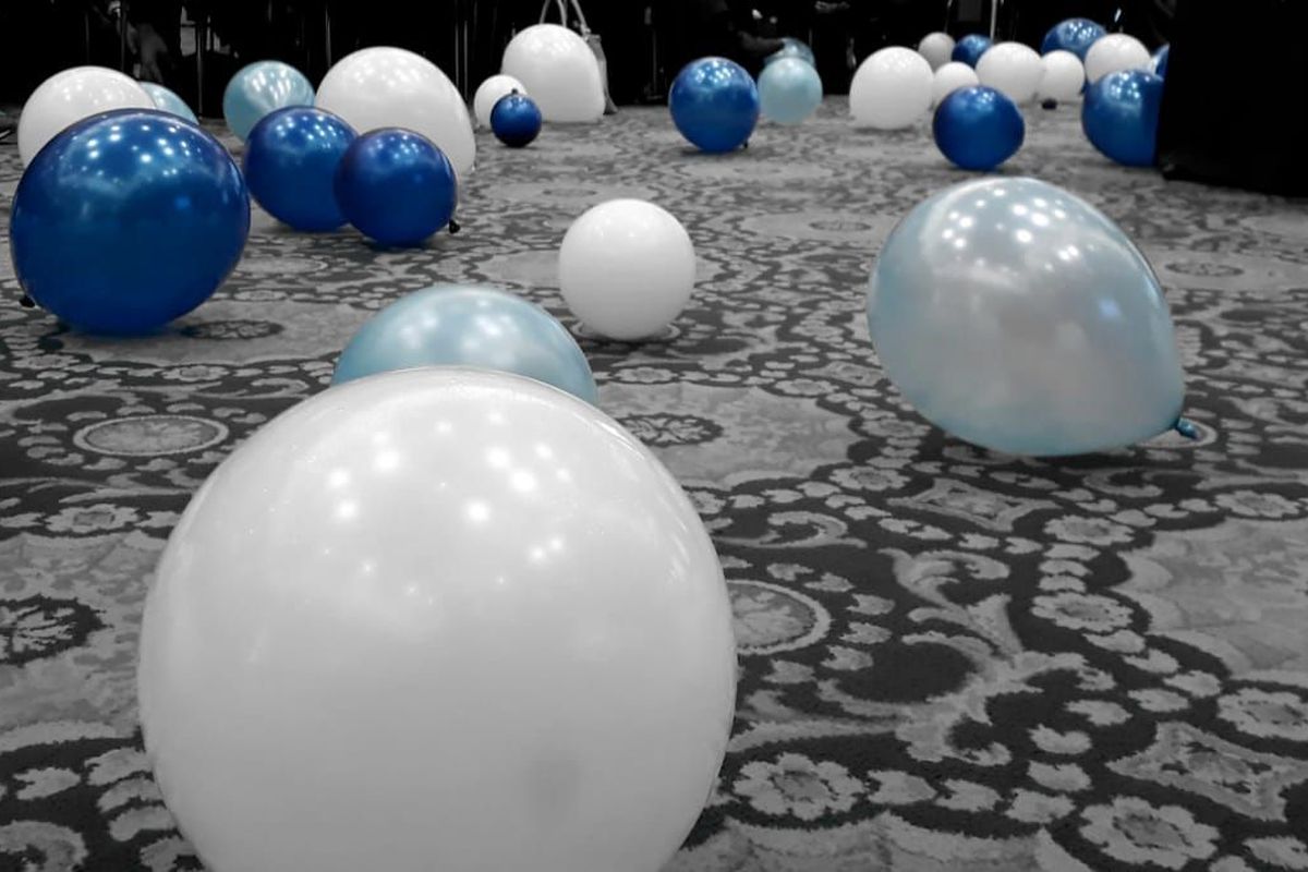 Luftballons in weiß und blau liegen auf dem Boden verteilt